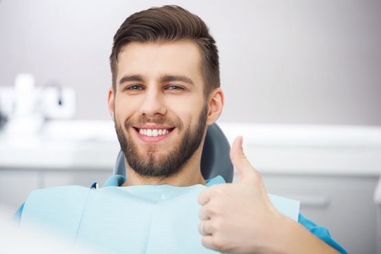 Mann beim Zahnarzt zeigt mit Daumen nach oben